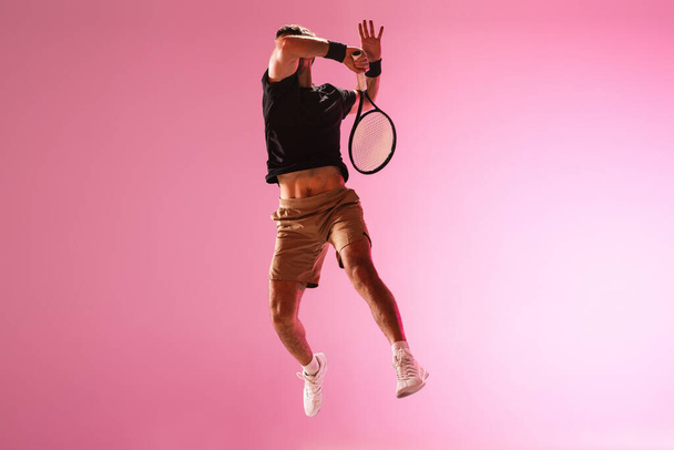 Young caucasian man playing tennis isolated on pink studio background, action and motion concept - Foto, Imagem