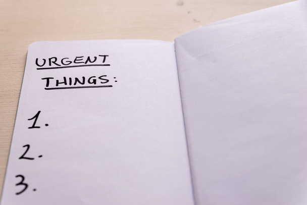 Página de diario blanco, escrito "Urgenti cosas" a mano con marcador negro. Lista de cosas urgentes que hacer. - Foto, Imagen