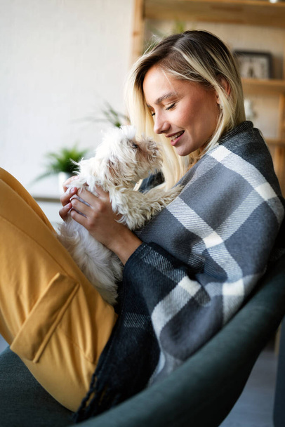 Lifestyle woman with her dog relaxing in living room. Happiness is a warm puppy. - Foto, afbeelding