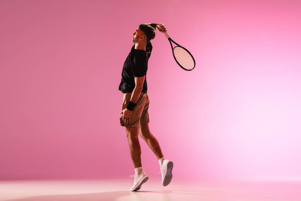 Young caucasian man playing tennis isolated on pink studio background, action and motion concept - Fotoğraf, Görsel