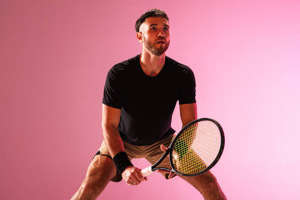 Молодой кавказский человек играет в теннис изолированы на розовом фоне студии, действие и движение концепции - Фото, изображение
