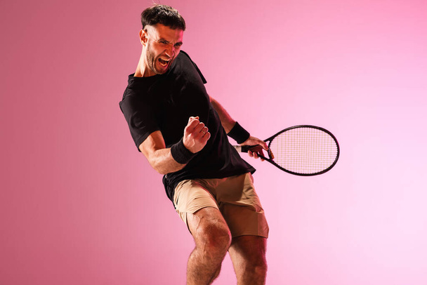 Young caucasian man playing tennis isolated on pink studio background, action and motion concept - Valokuva, kuva