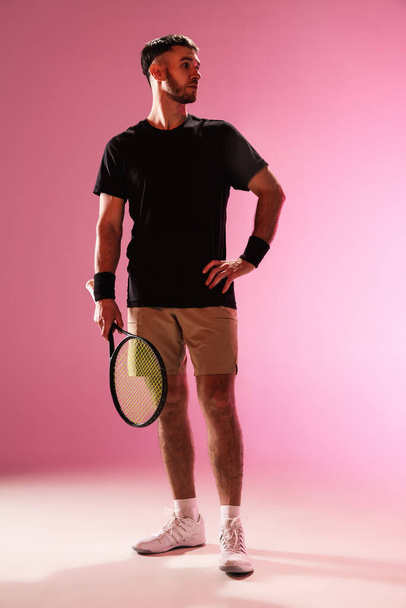 Young caucasian man playing tennis isolated on pink studio background, action and motion concept - Fotoğraf, Görsel