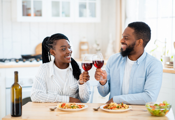 Fechas de cuarentena. Feliz pareja negra bebiendo vino y almorzando en casa - Foto, Imagen