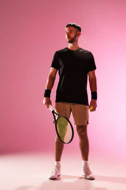 Young caucasian man playing tennis isolated on pink studio background, action and motion concept - Foto, afbeelding