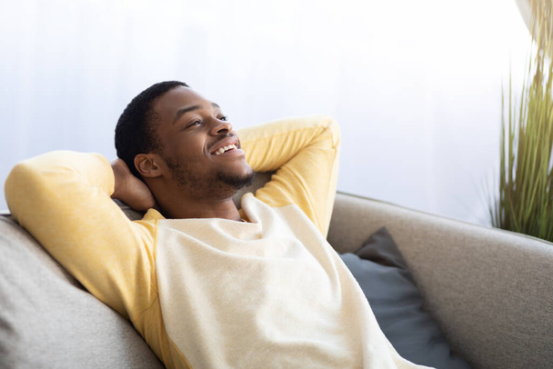 Closeup of black guy relaxing on couch at home - Zdjęcie, obraz