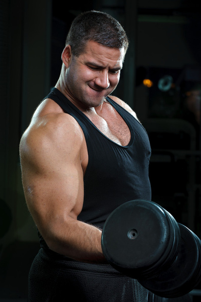 Strong muscular man training body in gym. - Фото, изображение