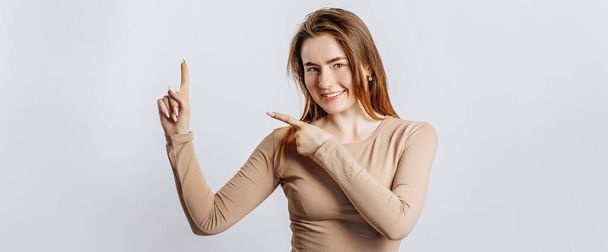 Beautiful young brunette girl smiling and pointing her fingers to the side at on a white isolated background - Zdjęcie, obraz