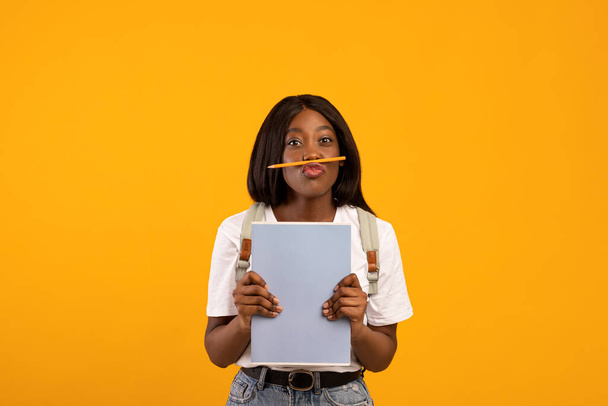 Αστεία μαύρη μαθήτρια με σακίδιο και σημειωματάρια - Φωτογραφία, εικόνα