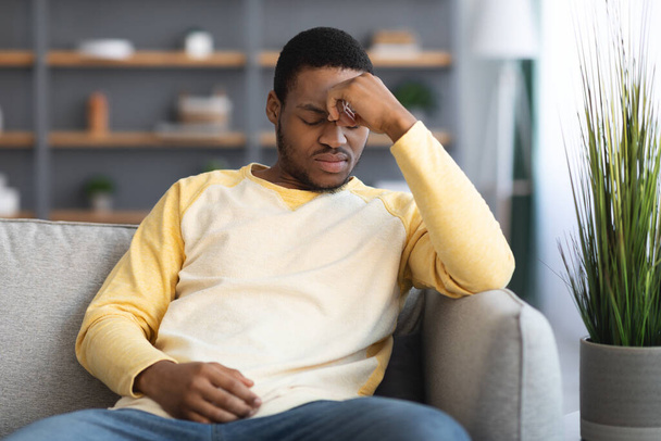 Depressed black guy sitting on couch alone at home - Φωτογραφία, εικόνα