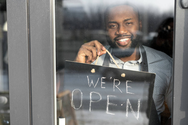 An African-American cafe owner with open sign - Foto, afbeelding
