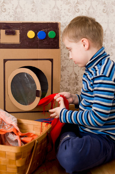 Çamaşır servisi. Çocuk ev yapımı karton çamaşır makinesiyle çamaşır yıkıyor.. - Fotoğraf, Görsel