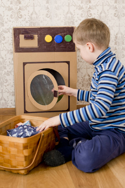 wasservice. kind doet wasserij met zelfgemaakte golfkarton wasmachine. - Foto, afbeelding