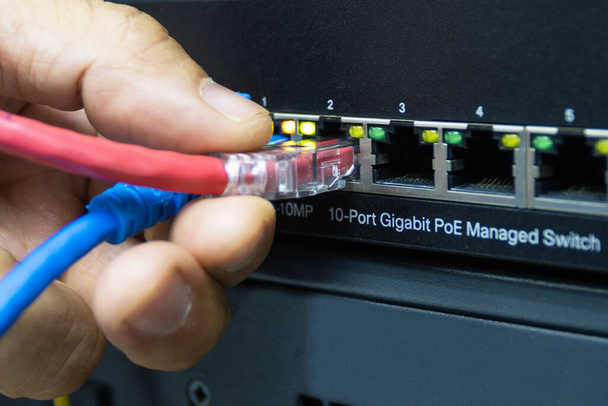Technicus aansluiten kabel netwerk om poort te schakelen in de serverruimte, Concept internet netwerk beheerders - Foto, afbeelding