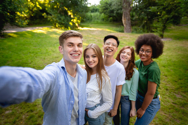 Group of multiethnical teen friends talking selfie outdoors in park - Фото, изображение