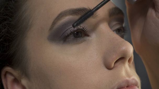 Tiro de visagista aplicando rímel negro en los ojos - Foto, imagen