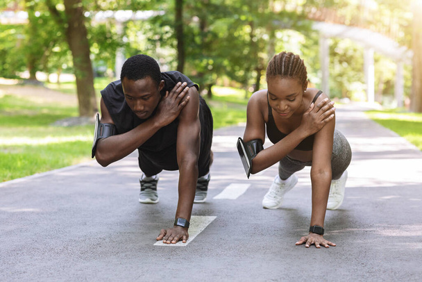 Чорношкіра спортсменка пара робить одну ручну вправу разом, тренування на відкритому повітрі
 - Фото, зображення