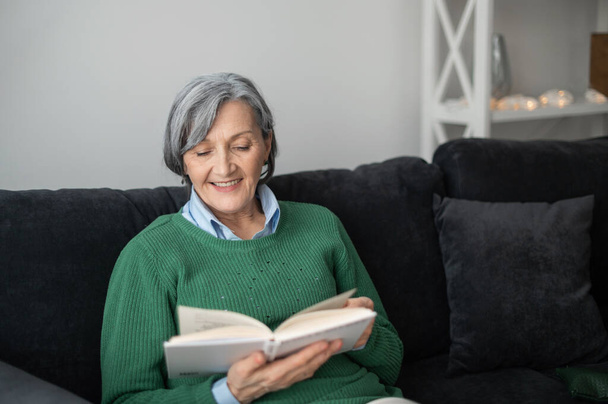 Grandmother in a green sweater reading a book - Foto, Imagem