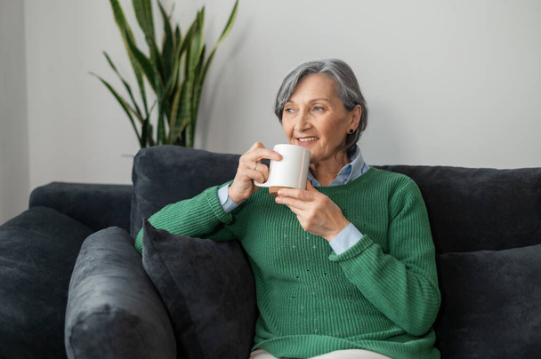 Senior lady daydreaming and enjoying a hot drink - Foto, Imagen