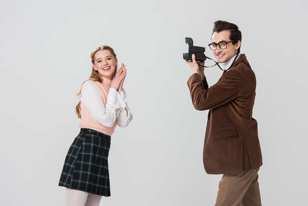 happy woman in retro clothes posing near man with vintage camera isolated on grey - 写真・画像