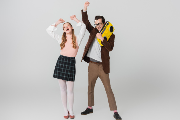 cheerful man holding vintage boombox while dancing with excited woman on grey - Photo, Image