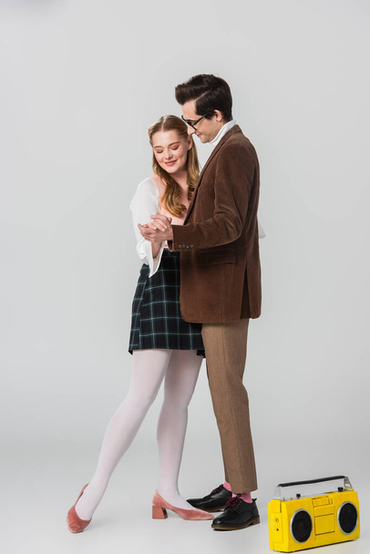 full length view of couple in retro outfit dancing near vintage tape recorder on grey - Foto, Imagem