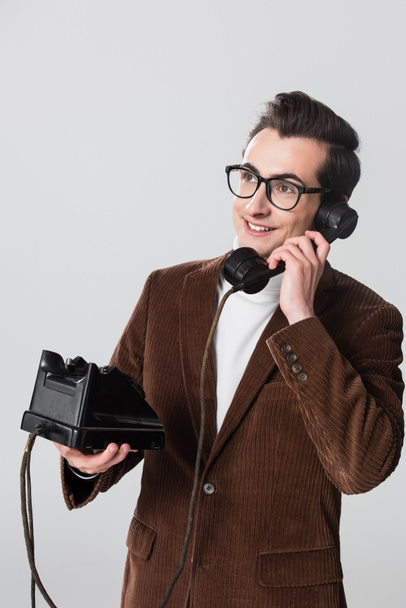happy man in velvet blazer looking away while calling on vintage phone isolated on grey - Photo, Image