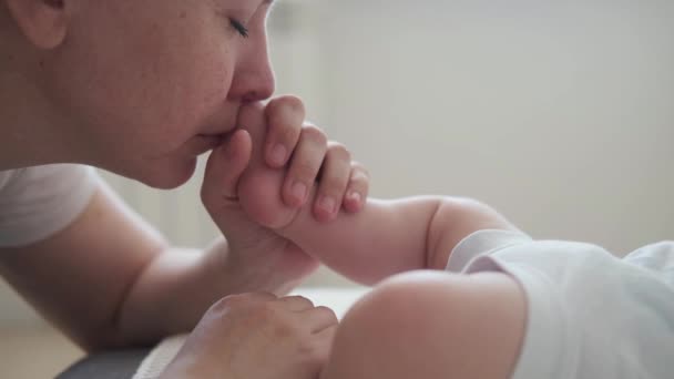 4 bin. Çekici, mutlu anne, küçük erkek bebek ayak parmaklarını kokla. Mutlu aile - Video, Çekim