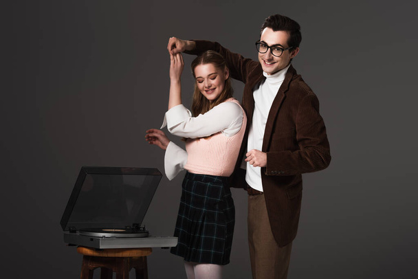 happy, old fashioned couple dancing near record player isolated on black - Foto, Imagem