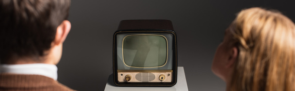 back view de homem e mulher desfocados assistindo tv vintage isolado em cinza, banner - Foto, Imagem