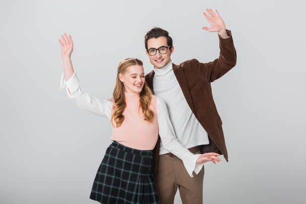 fröhliches Paar im Retro-Stil tanzt mit erhobenen Händen isoliert auf grau - Foto, Bild