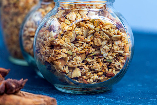 Freshly baked granola, muesli from oat flakes, varius of nuts, honey, pumpkin seeds in glass jar. Home cooking healthy vegetarian snack. Homemade food concept. Keto diet - Photo, image