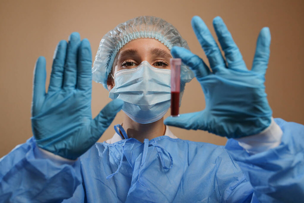 Pielęgniarka trzyma probówkę z dodatnim wynikiem testu na obecność koronawirusu i pokazuje znak STOP ręką. Pandemia nCoV 2019 powstrzyma koronawirusa. MERS Przewodniczący.  - Zdjęcie, obraz