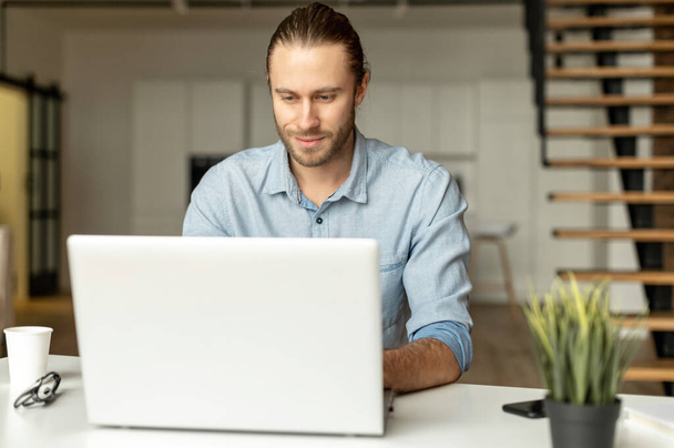A guy in smart casual wear is using a laptop - Foto, afbeelding