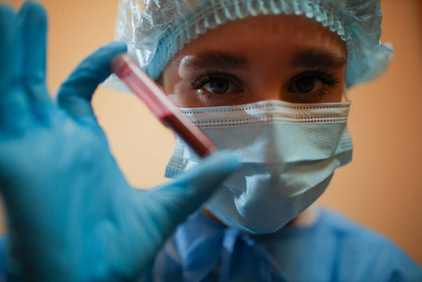 Медсестра держит пробирку с коронавирусом положительный образец крови из Ухана, Китай. Пандемия NCoV в 2019 году. остановить коронавирус. Мерс. Вирусолог думает о коронавирусной вакцине. грипп, птичий грипп - Фото, изображение
