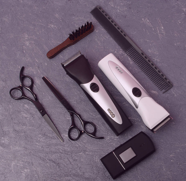 Ensemble d'outils professionnels de coiffeur avec peignes, ciseaux, tondeuse à cheveux, rasoir et pinceau sur fond gris. Vue du dessus Maquette - Photo, image