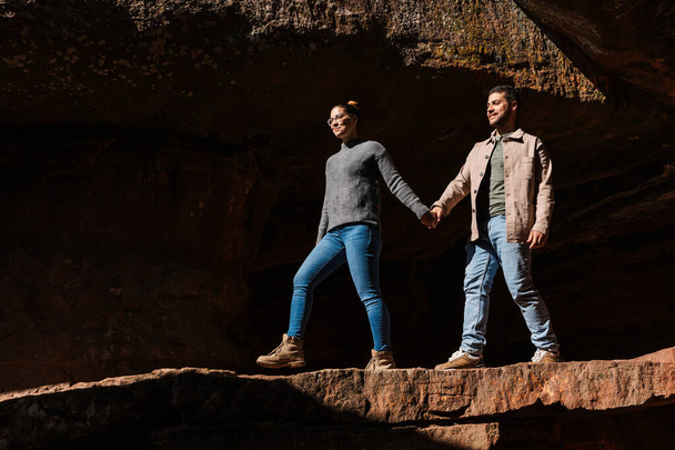 una coppia cammina mano nella mano attraverso un paesaggio roccioso, la ragazza che guida il ragazzo. - Foto, immagini