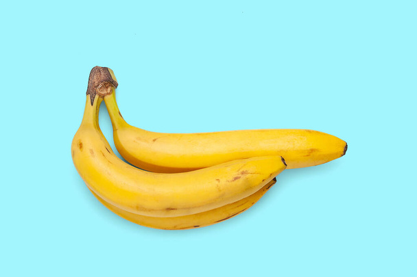 Banany odizolowane na niebieskim tle. Trzy dojrzałe żółte banany. Banda bananów na Sinempoverhnosti. Egzotyczne, tropikalne owoce. Tradycyjny kąt. Zdrowe odżywianie. - Zdjęcie, obraz