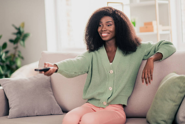 Foto de joven alegre afro mujer feliz sonrisa positiva canal interruptor ver película descanso fin de semana sentarse sofá en casa - Foto, Imagen