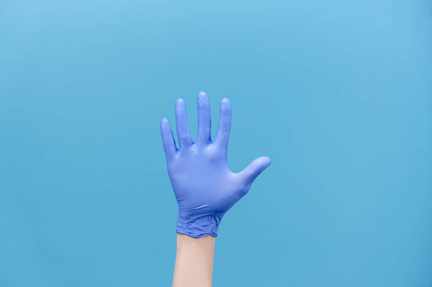 Numbers calculating. Close up of unrecognizable young man counting from 5 with fingers, wears medical protectives gloves, isolated on blue background with copy space for advertisement. Hand gesture - Фото, изображение