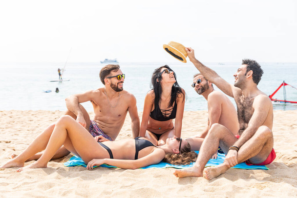 Happy friends relaxing on the beach in Barcelona - Multiracial group of best friends enjoying summer time together and having fun - Happiness and friendship during a travel in Spain - Photo, image