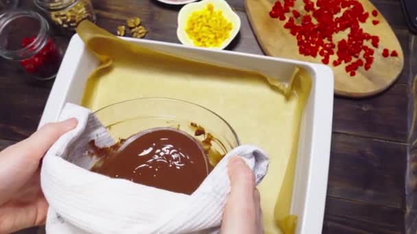 Crop gospodyni domowa nalewanie czekolady w formie pieczenia z pergaminem - Materiał filmowy, wideo