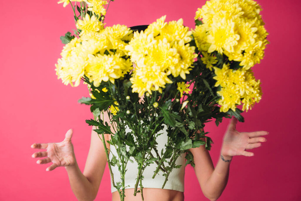 Stylish woman in hat on pink red background throwing to camera large bouquet of yellow asters, spring mood, happy emotions isolated space - Fotografie, Obrázek