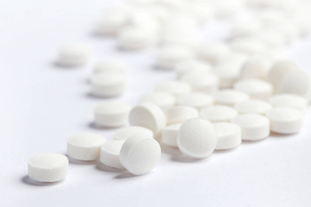 Bílé kulaté pilulky na bílém pozadí. Hromada malých kulatých léků. Koncepce zdravotní péče a medicíny - Fotografie, Obrázek