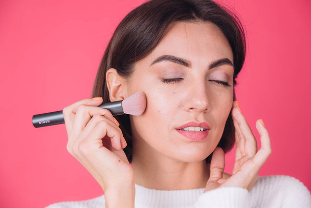 Woman in casual white sweater on pink red background with makeup on face hold blush brush isolated copy space beauty portrait - Φωτογραφία, εικόνα