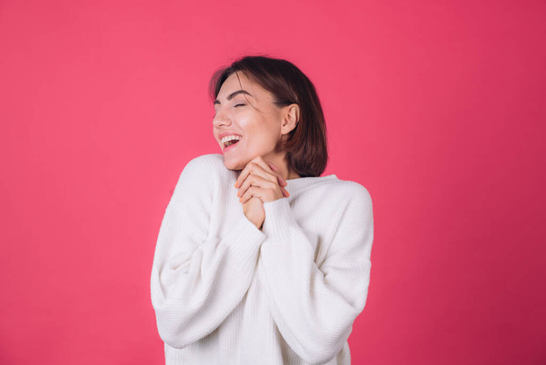 Woman in white casual sweater on red pink background copy space cheerful excited amazed with closed eyes - Photo, Image