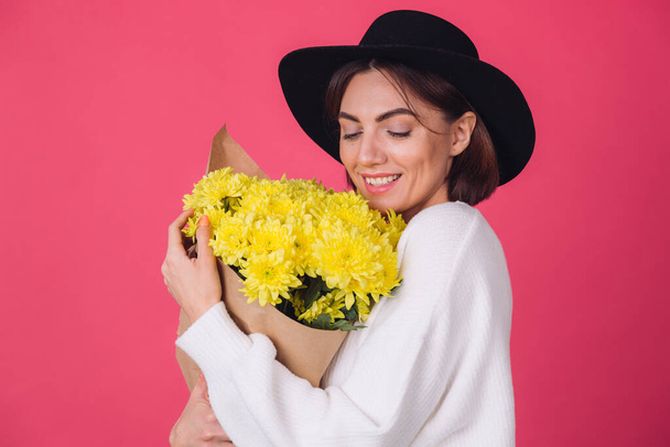 Κομψό γυναίκα στο καπέλο σε ροζ κόκκινο φόντο χαμόγελο κρατήσει μεγάλο μπουκέτο από κίτρινα λουλούδια, ανοιξιάτικη διάθεση, ευτυχισμένη συναισθήματα απομονωμένο χώρο  - Φωτογραφία, εικόνα