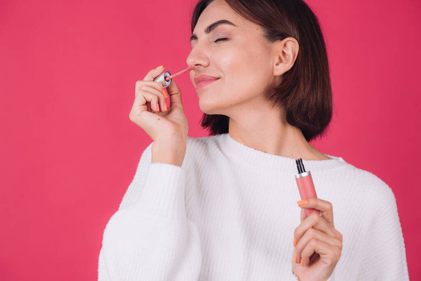 Stylish woman in casual white sweater on pink red background isolated space happy positive hold lipstick - Φωτογραφία, εικόνα