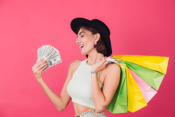 Tyylikäs nainen hattu vaaleanpunainen punainen tausta eristetty tila hymy innoissaan pidä tuuletin 100 dollaria rahaa ja ostoskassit, onnellinen positiivinen hymyillen - Valokuva, kuva