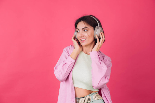 Happy positive woman in headphones on pink red background positive dancing moving enjoying sound - Foto, Imagem